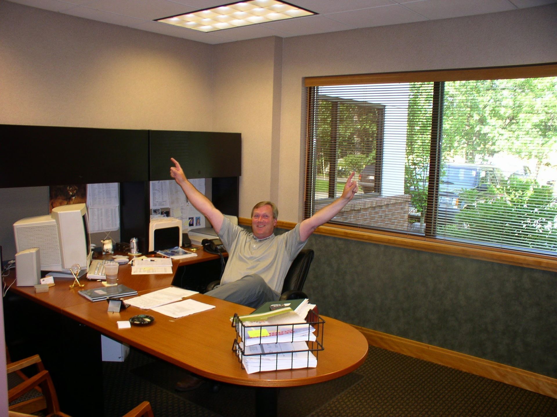 A man sits at a desk with his arms in the air