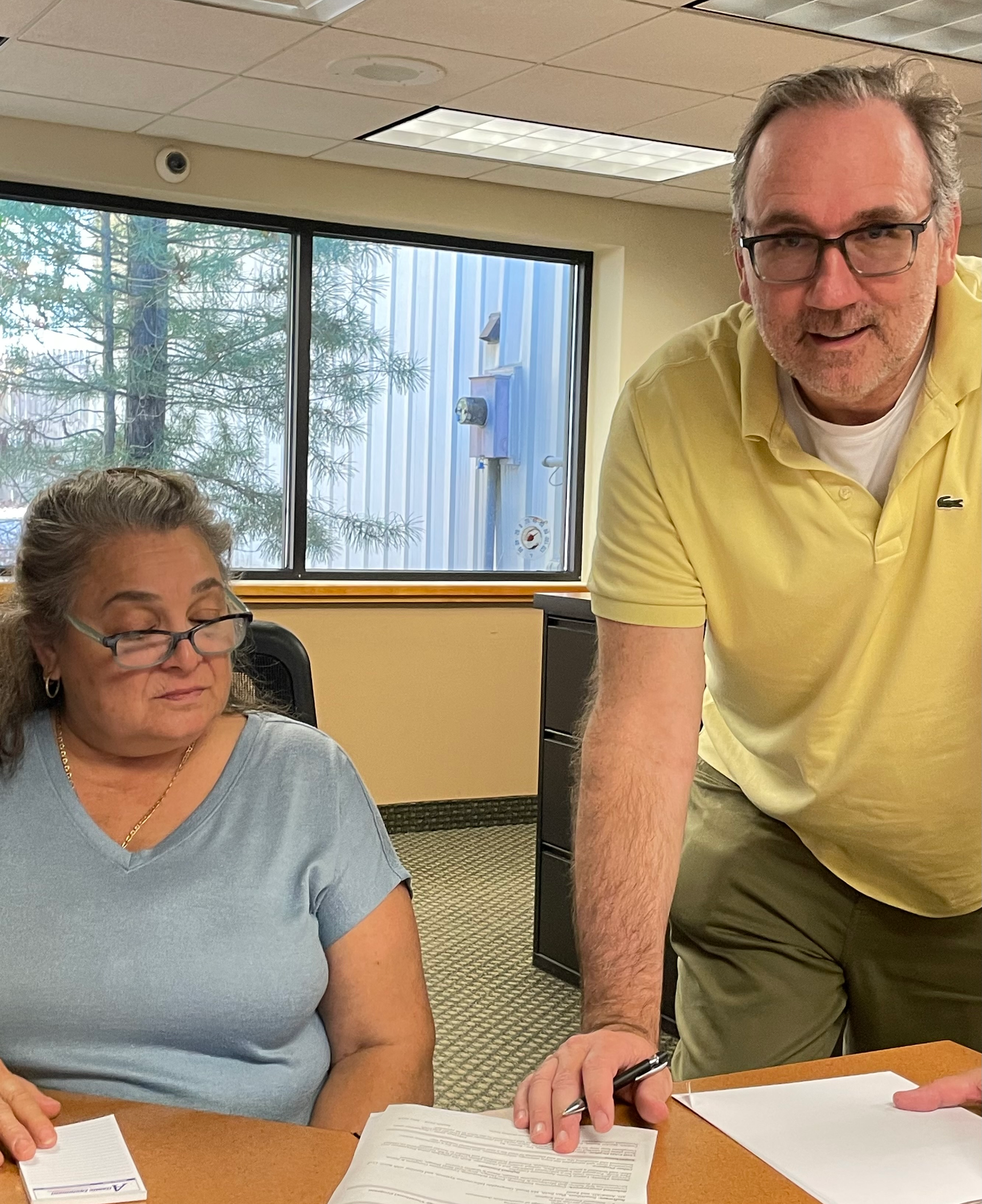 A man in a yellow shirt is standing next to a woman in glasses