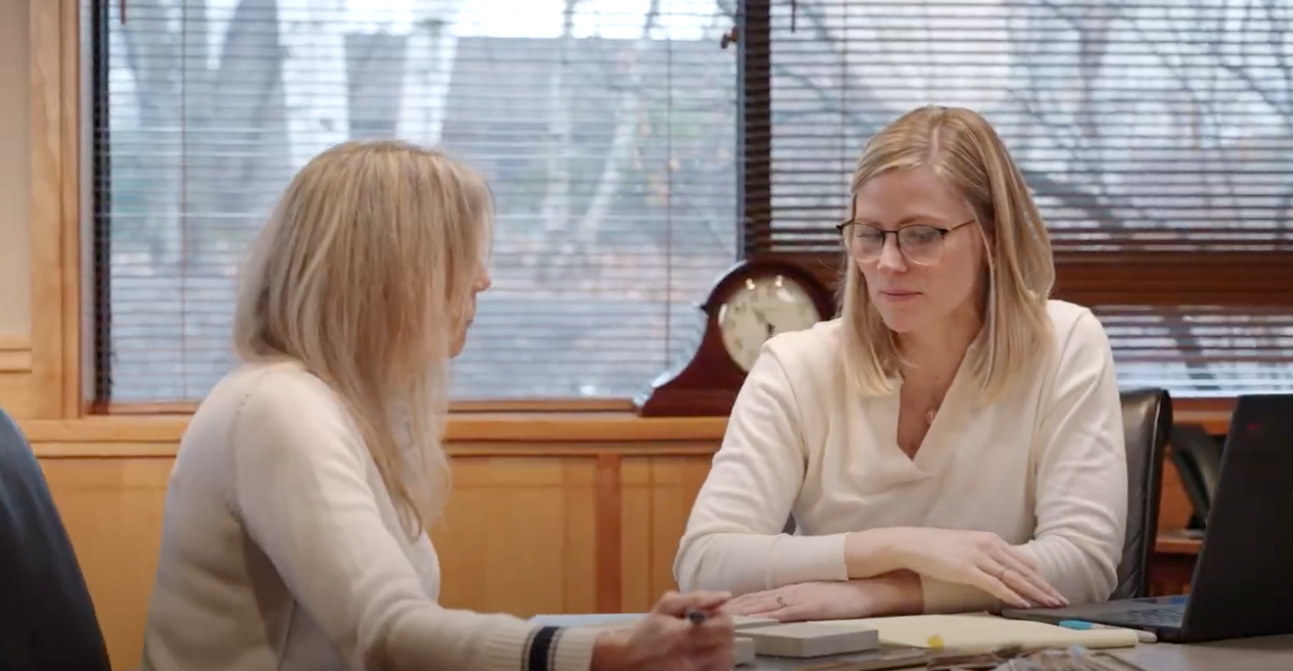 Two women are sitting at a table talking to each other.