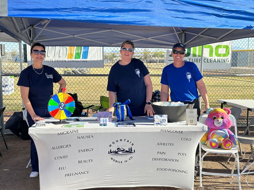 A group of people standing around a table under a tent.