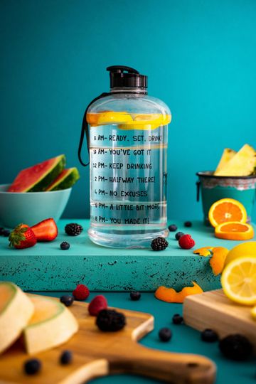 A bottle of water is sitting on a table next to fruit.