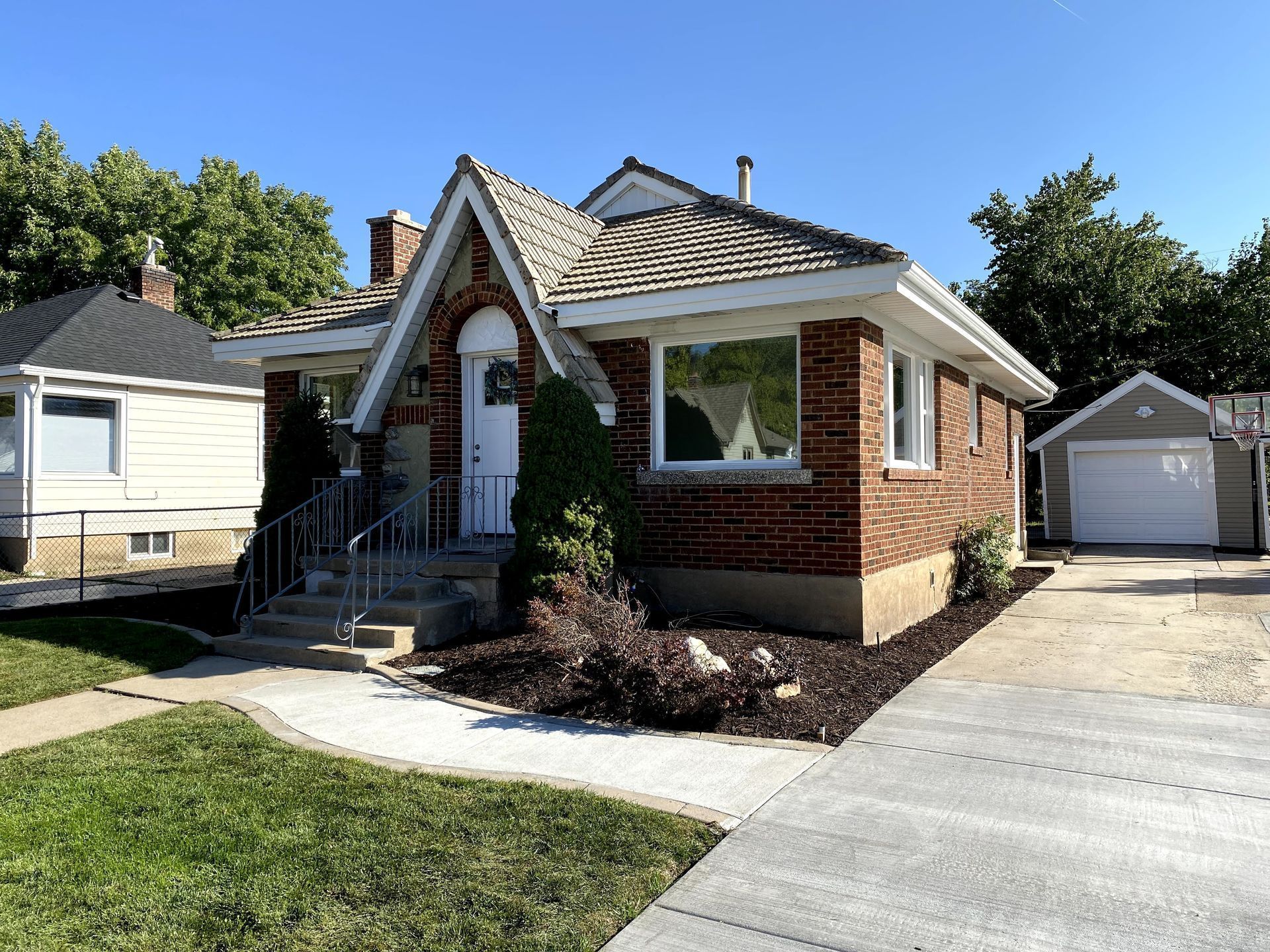 A small brick house with a garage in the backyard