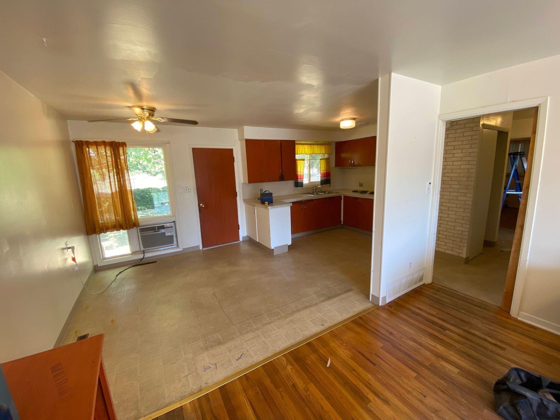 A living room with hardwood floors and a kitchen in a house.