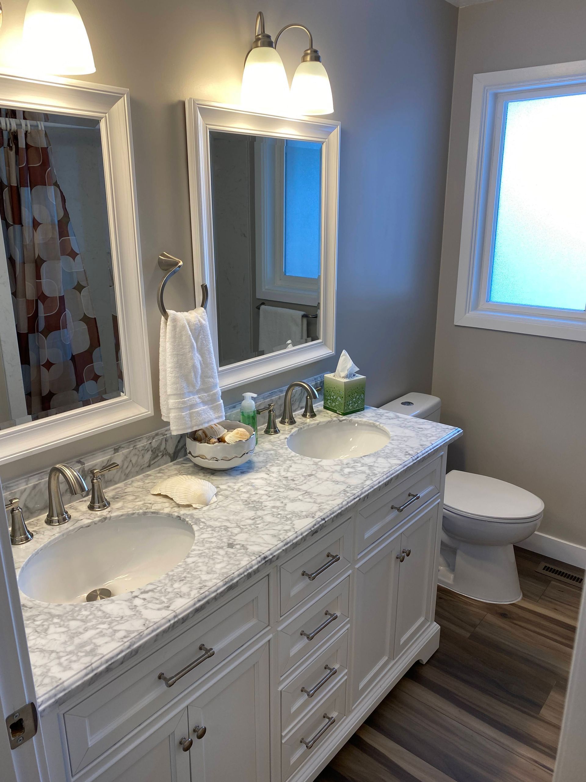 A bathroom with two sinks , a toilet , and a mirror.