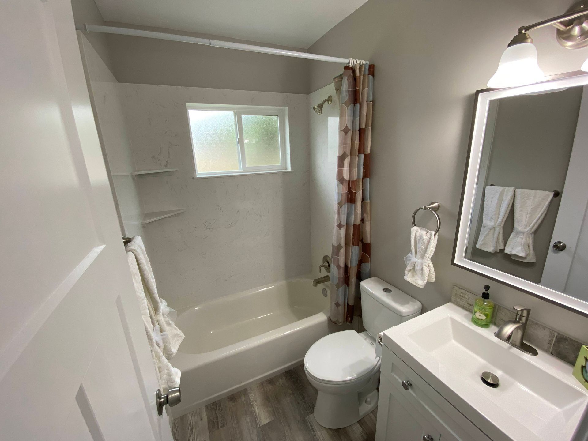 A bathroom with a tub , toilet , sink and mirror.