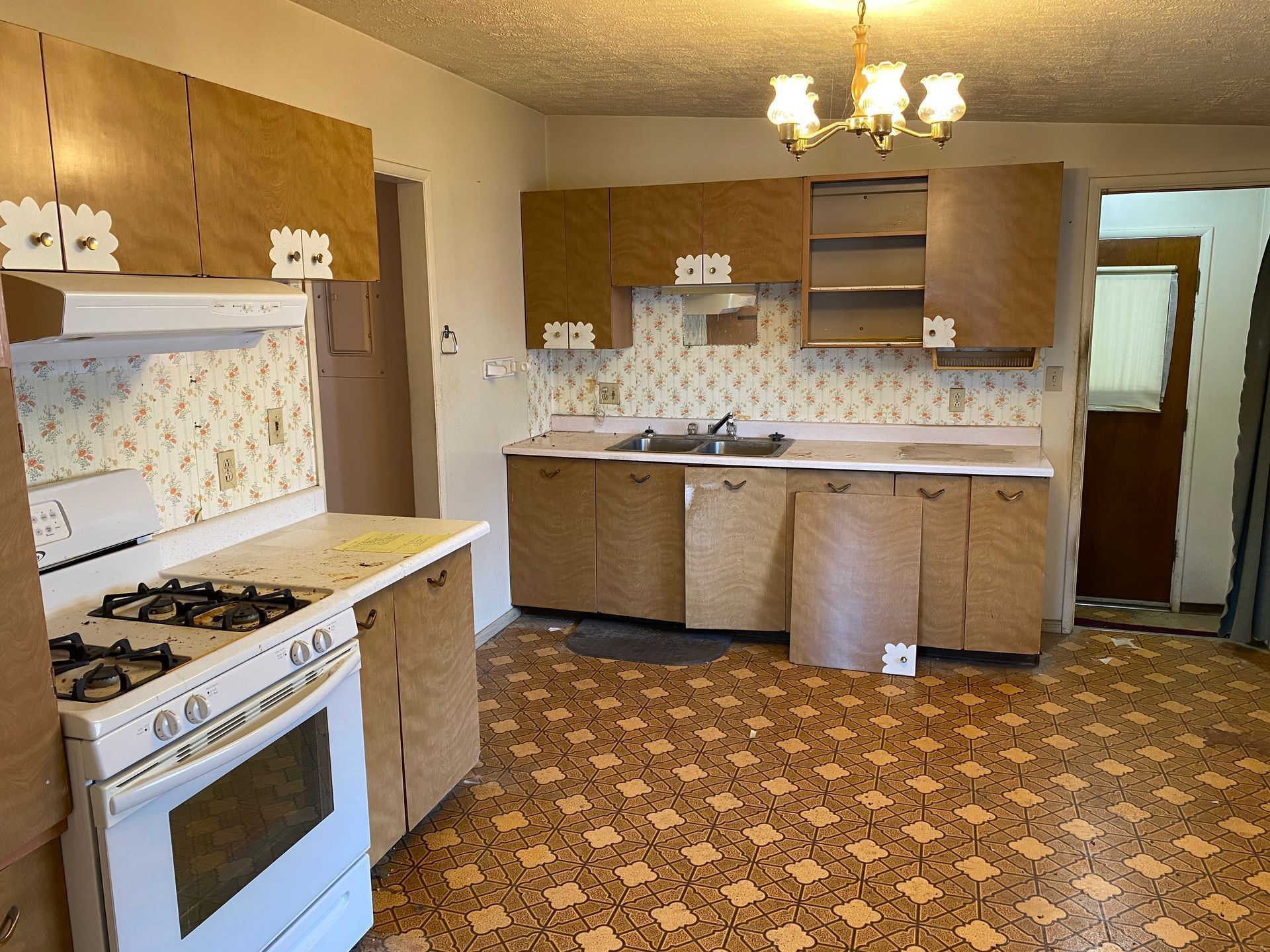 An empty kitchen with brown cabinets and a white stove