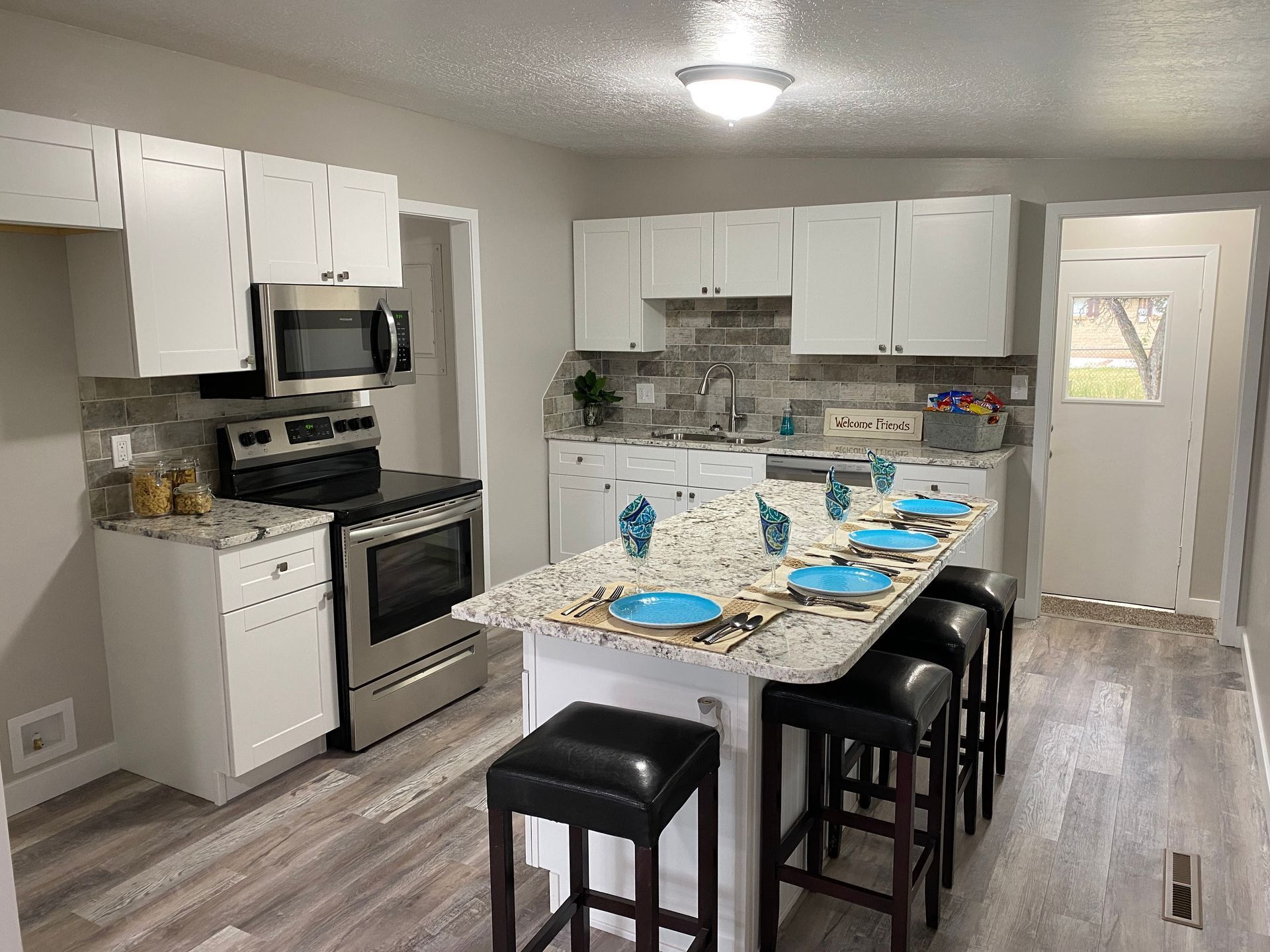 A kitchen with white cabinets , stainless steel appliances , and a large island.