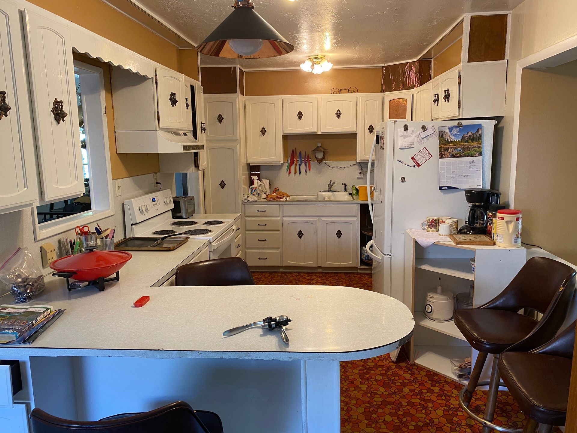 A kitchen with white cabinets , a refrigerator , a stove , and a table.