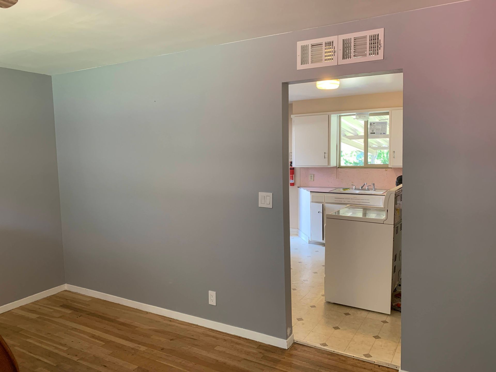 An empty room with a doorway leading to a kitchen.