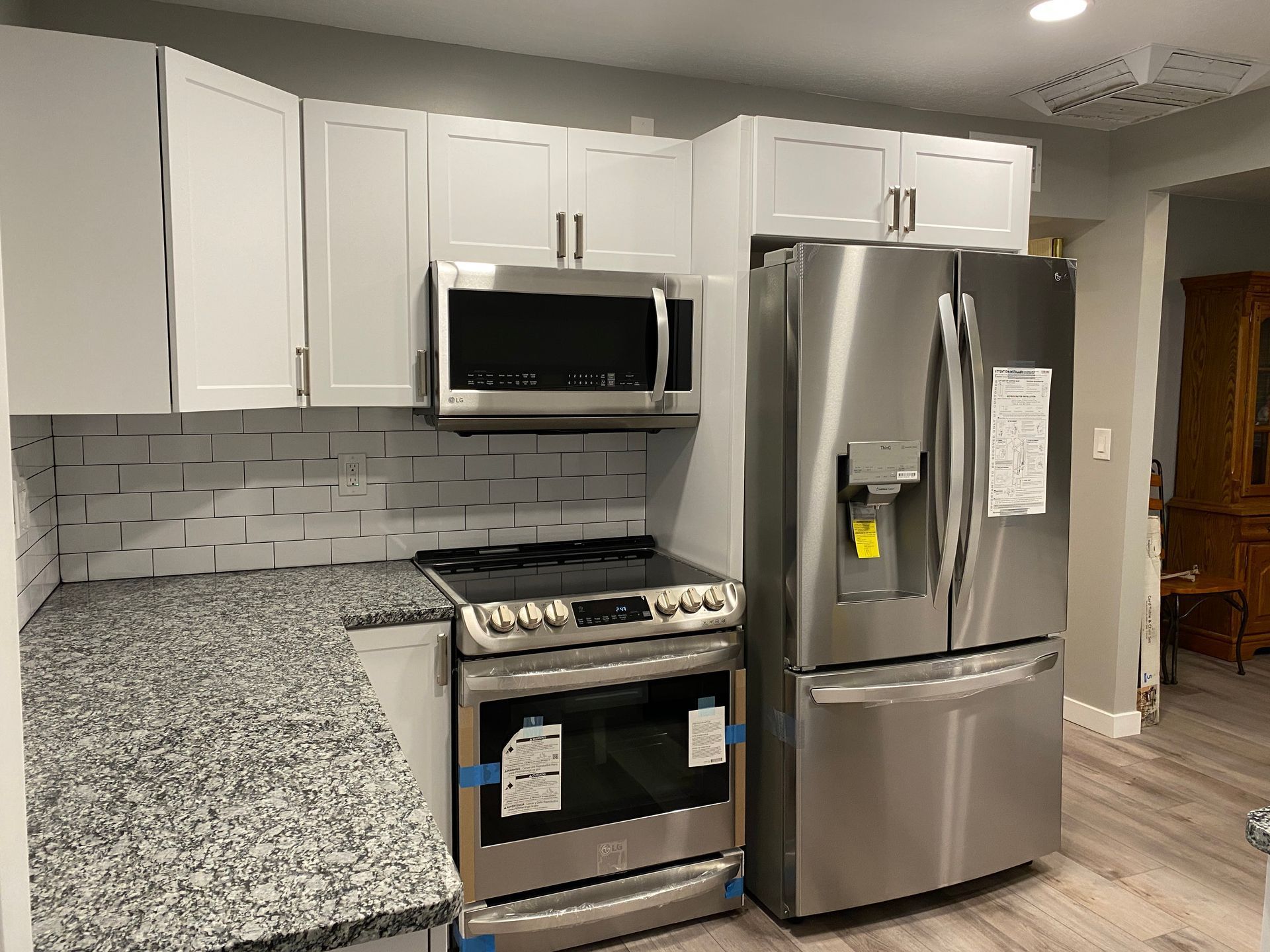 A kitchen with stainless steel appliances , granite counter tops , and white cabinets.