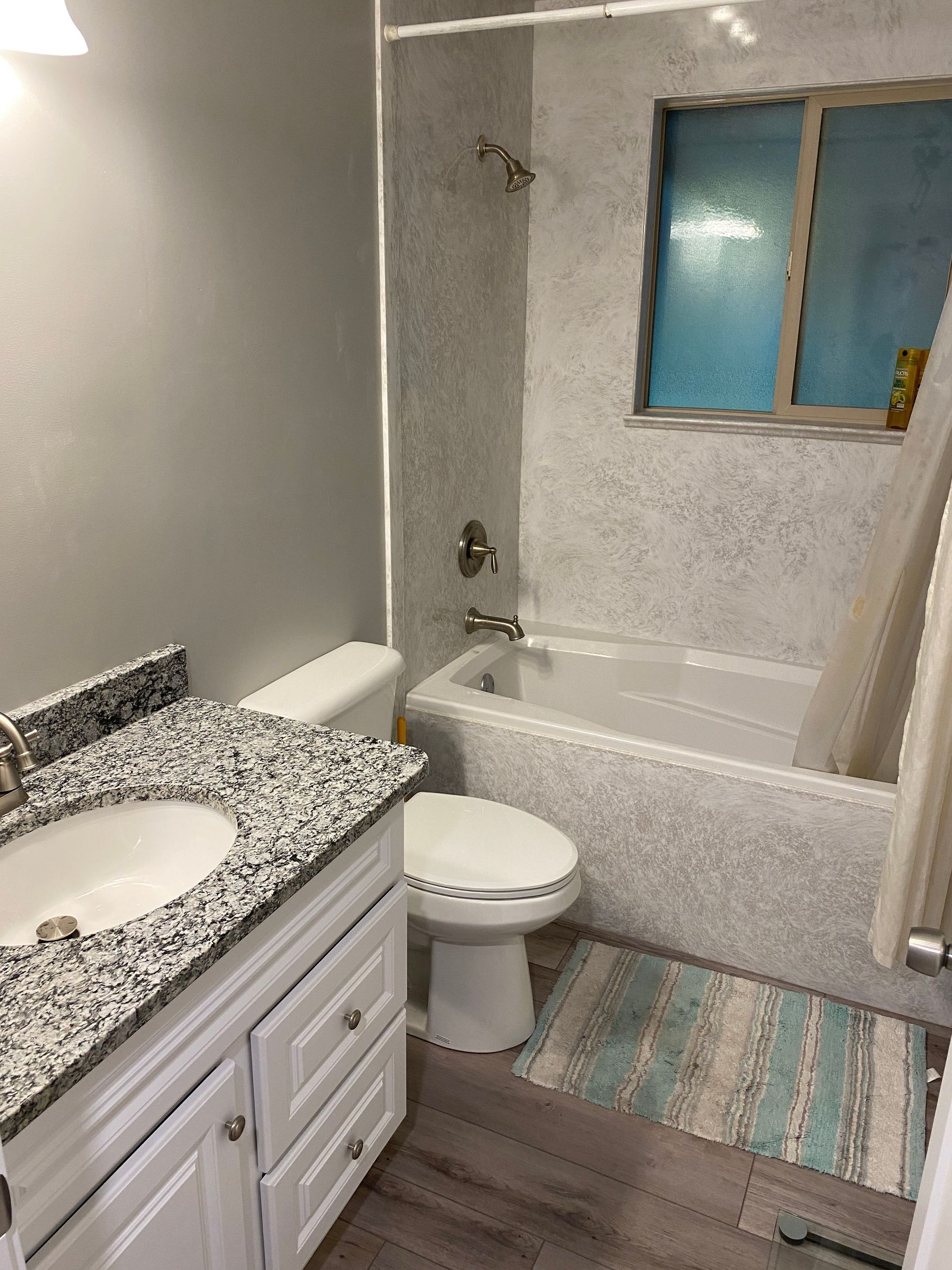 A bathroom with a toilet , sink and bathtub.