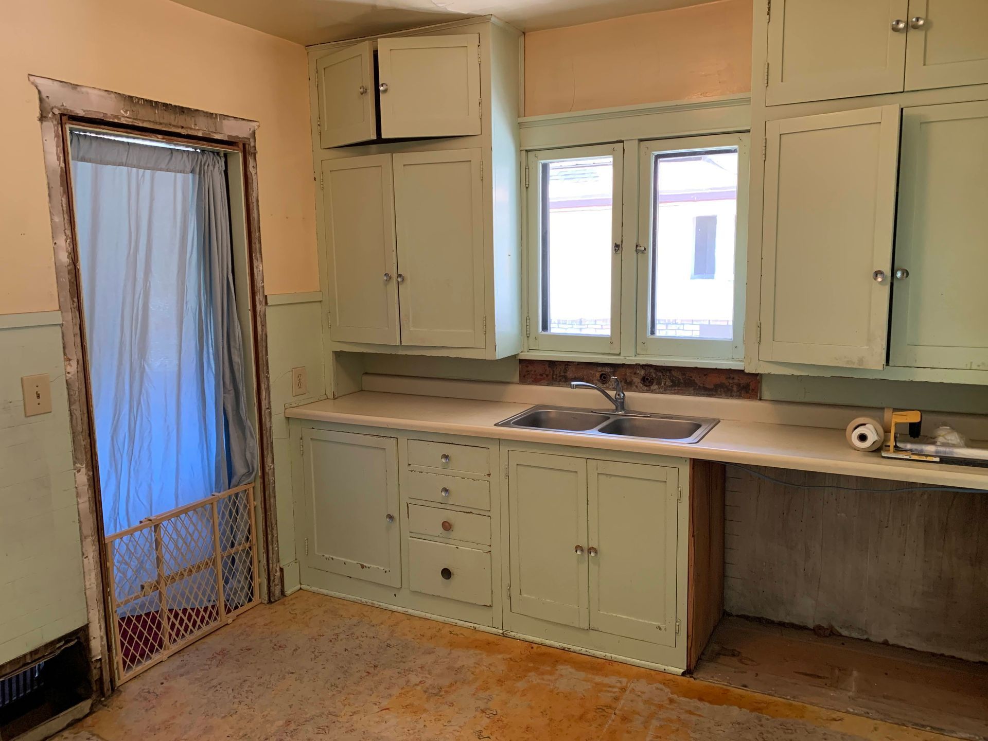 An empty kitchen with green cabinets and a sink.