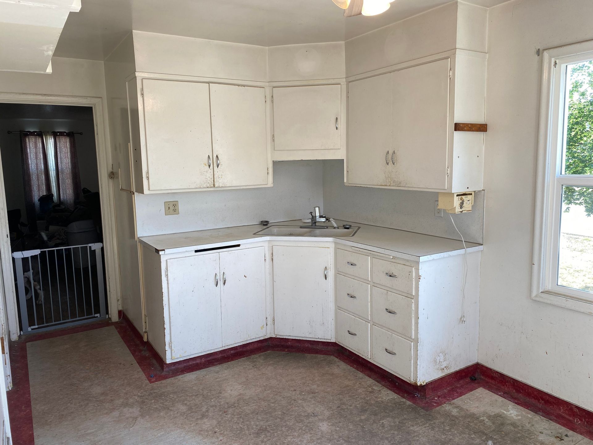 An empty kitchen with white cabinets and red floors