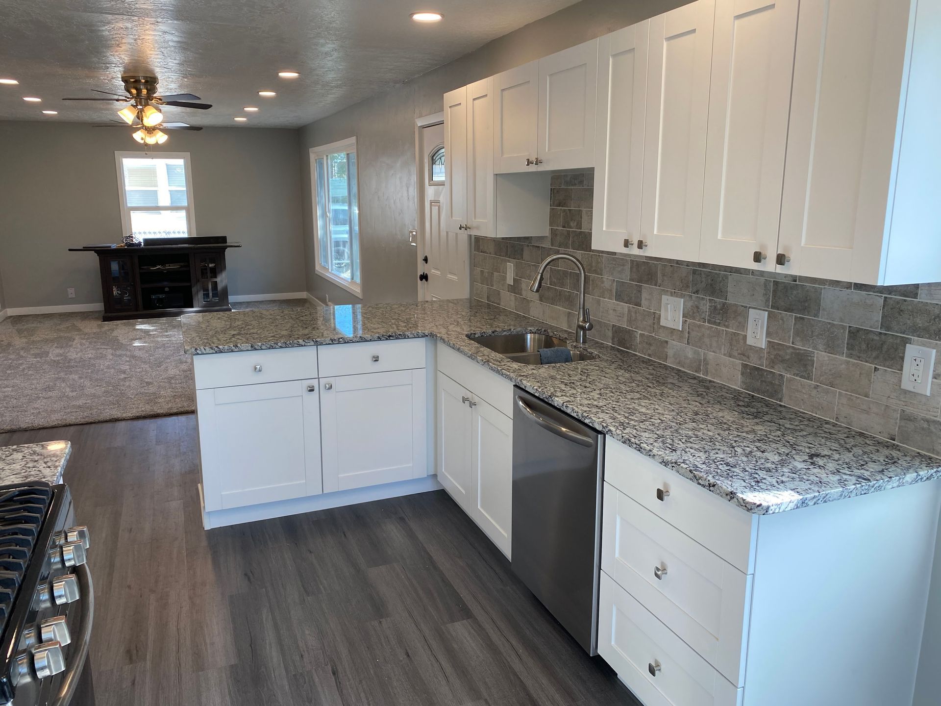 A kitchen with granite counter tops , white cabinets and stainless steel appliances.