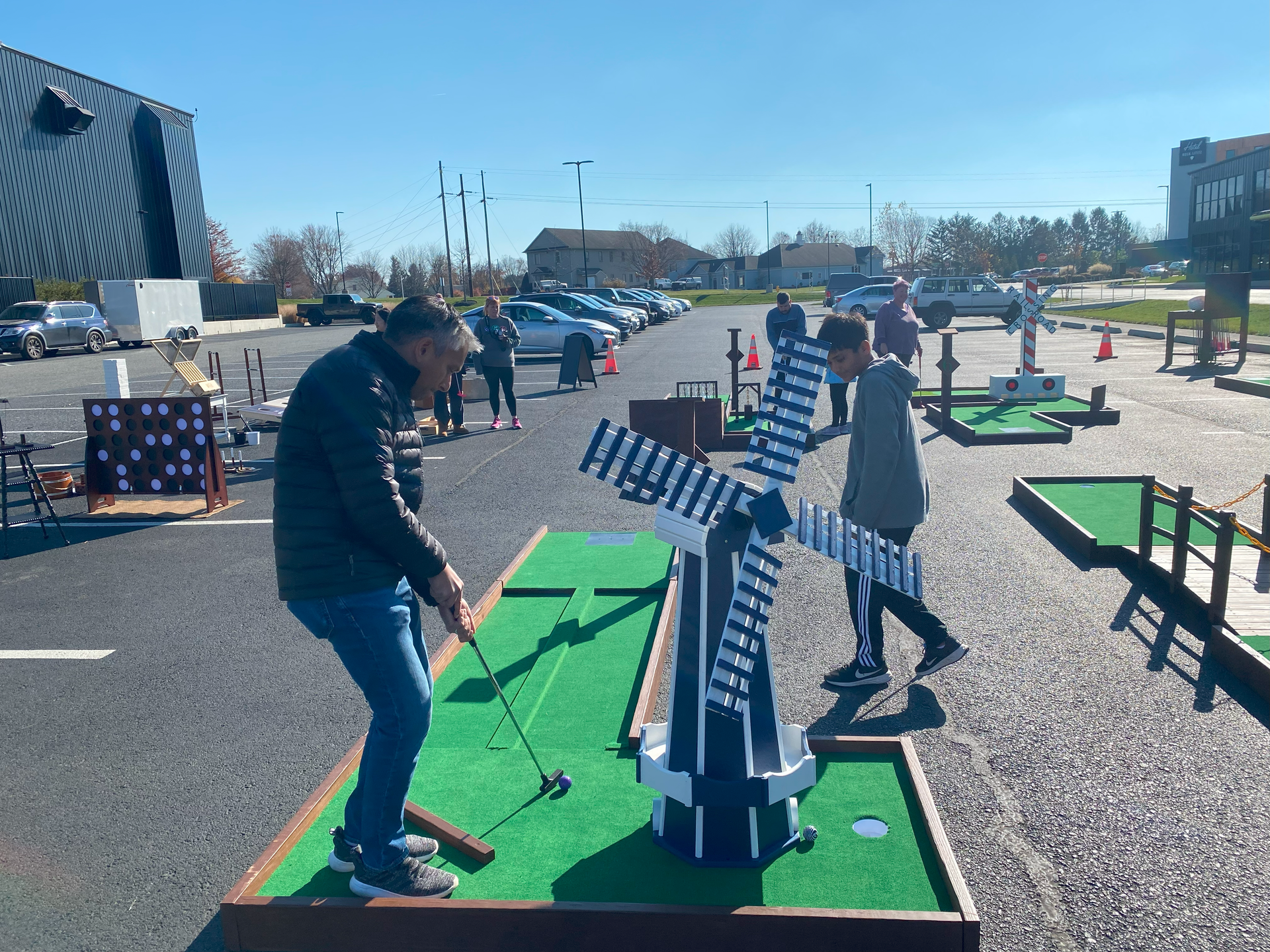 Two people are playing mini golf in a parking lot.