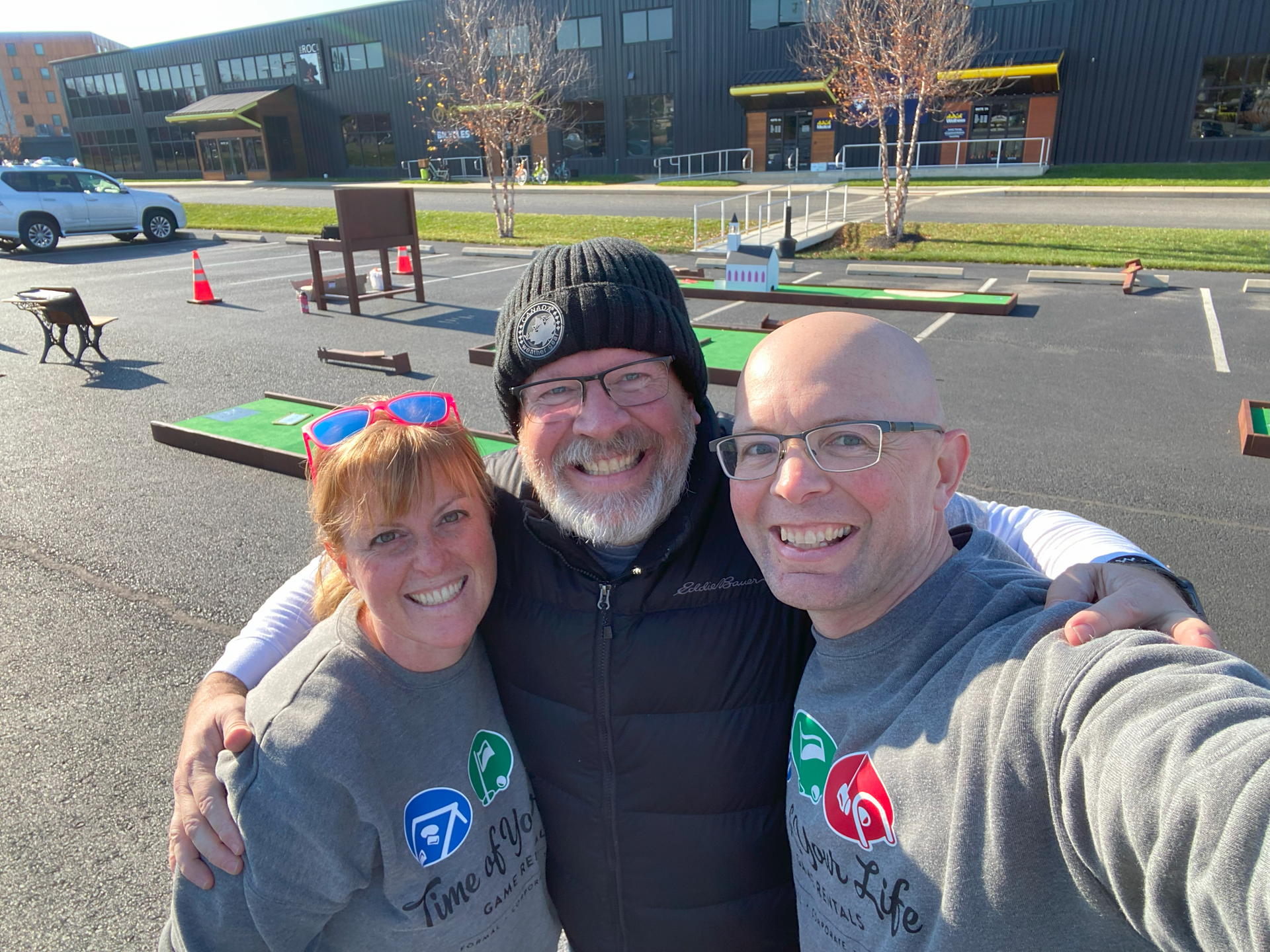Three people are posing for a picture in a parking lot.