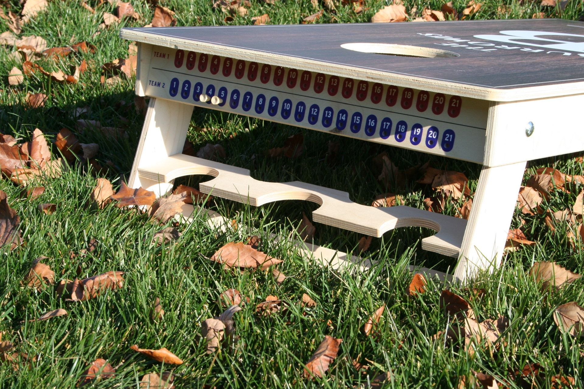 A cornhole board is sitting on top of a lush green field