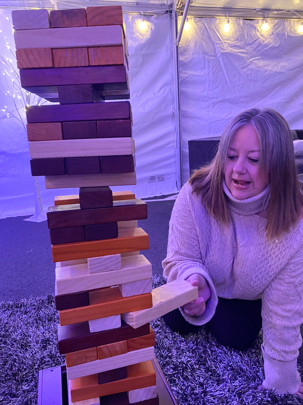 A woman is playing a game of jenga on the ground.