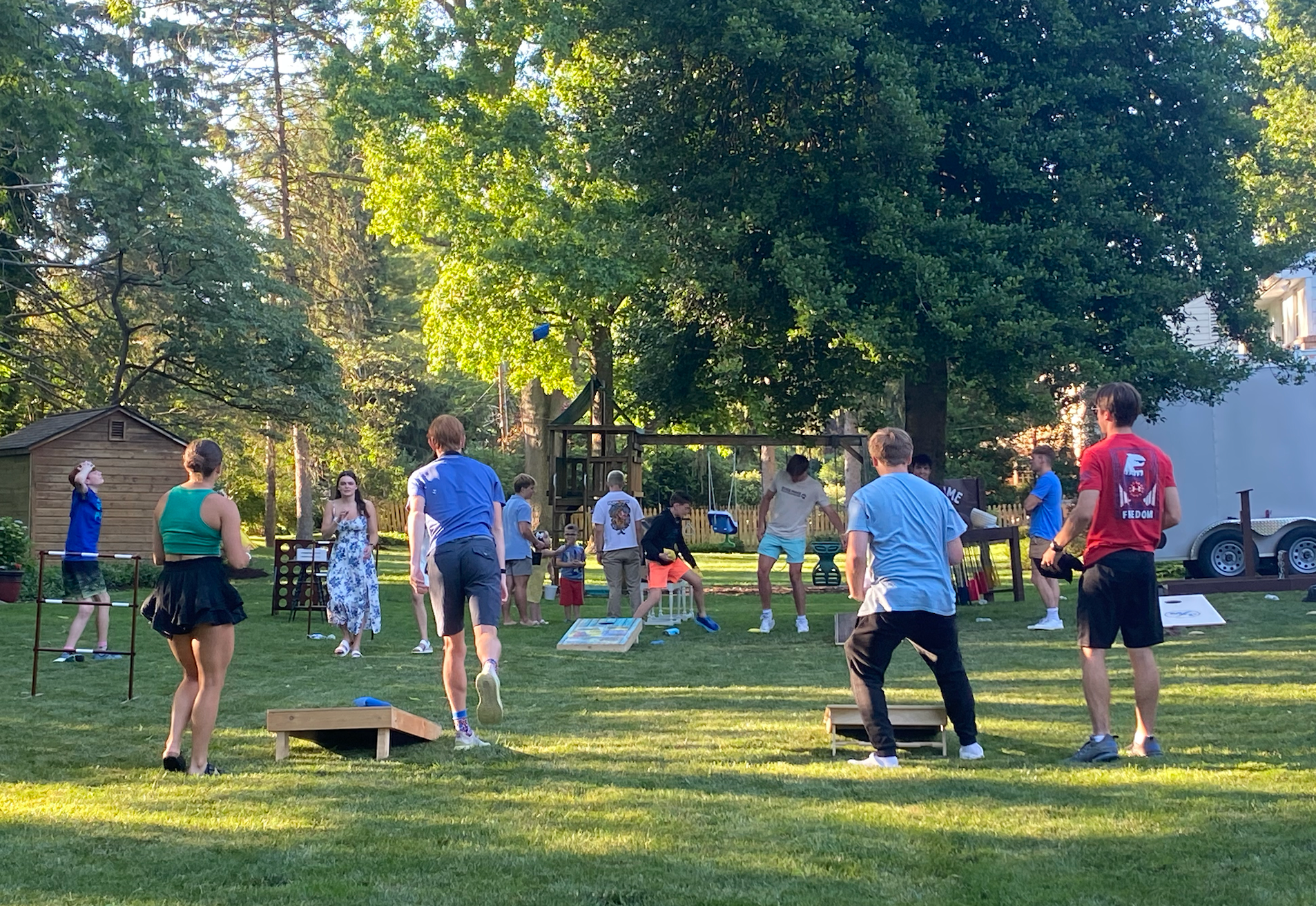 A group of people are playing cornhole in a park.