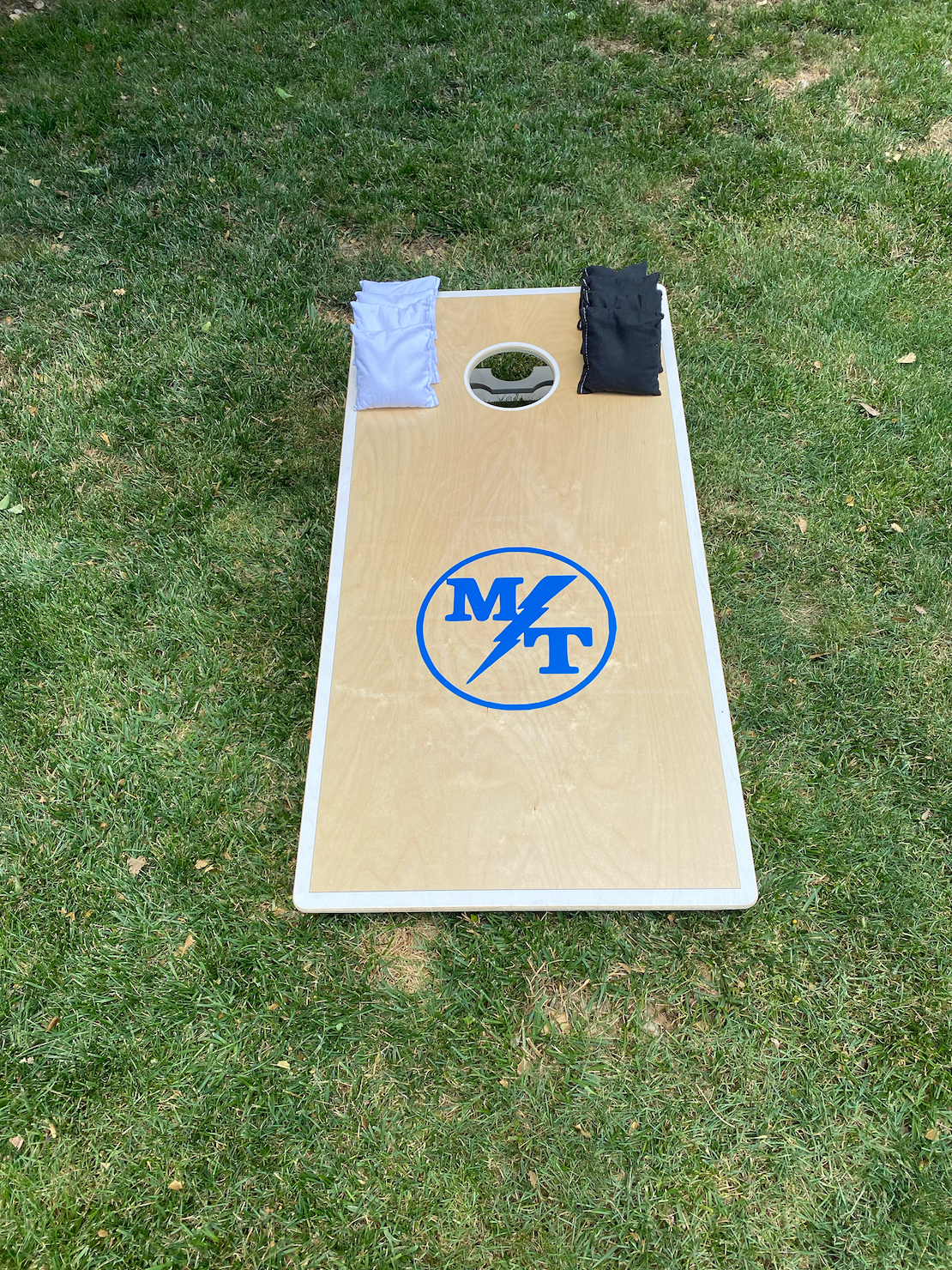 A cornhole board is sitting on top of a lush green field.
