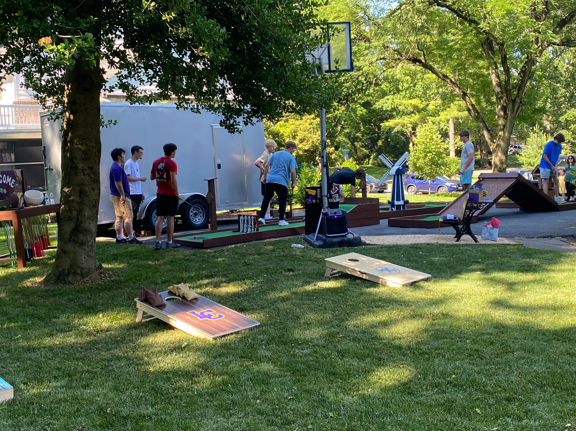 A group of people are playing cornhole in a park.