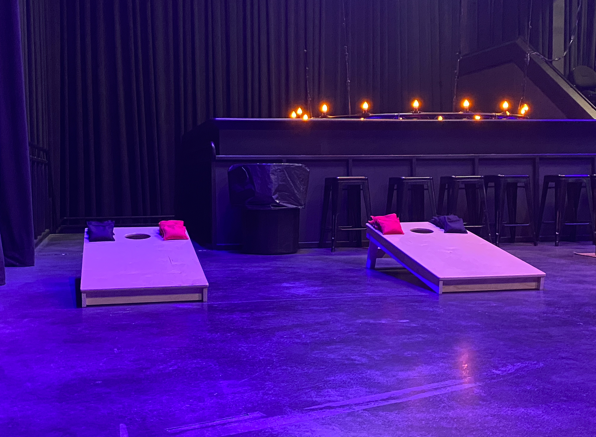 Two cornhole boards are sitting on the floor in a dark room.