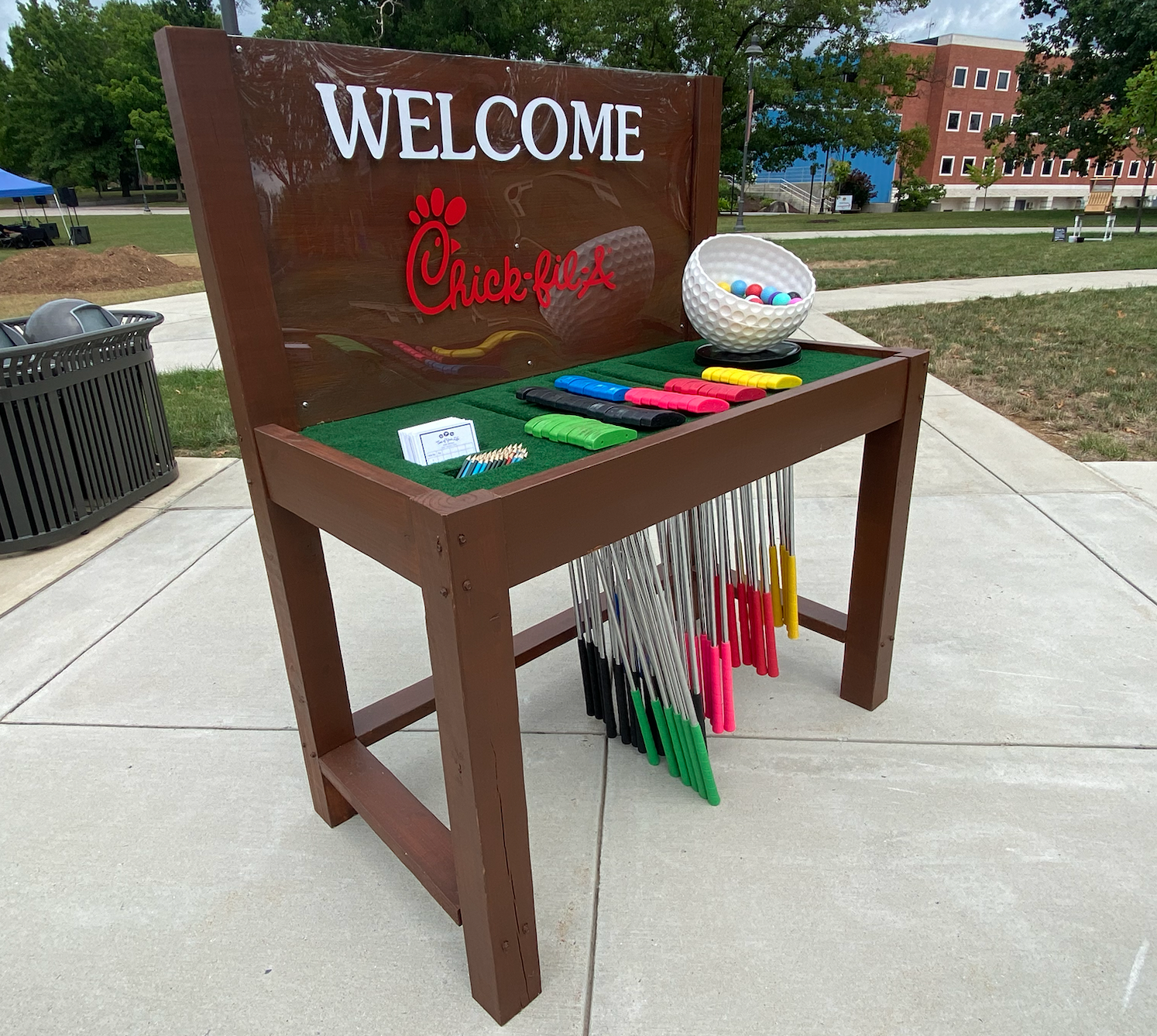 A welcome sign for chick-fil-a is on a wooden bench