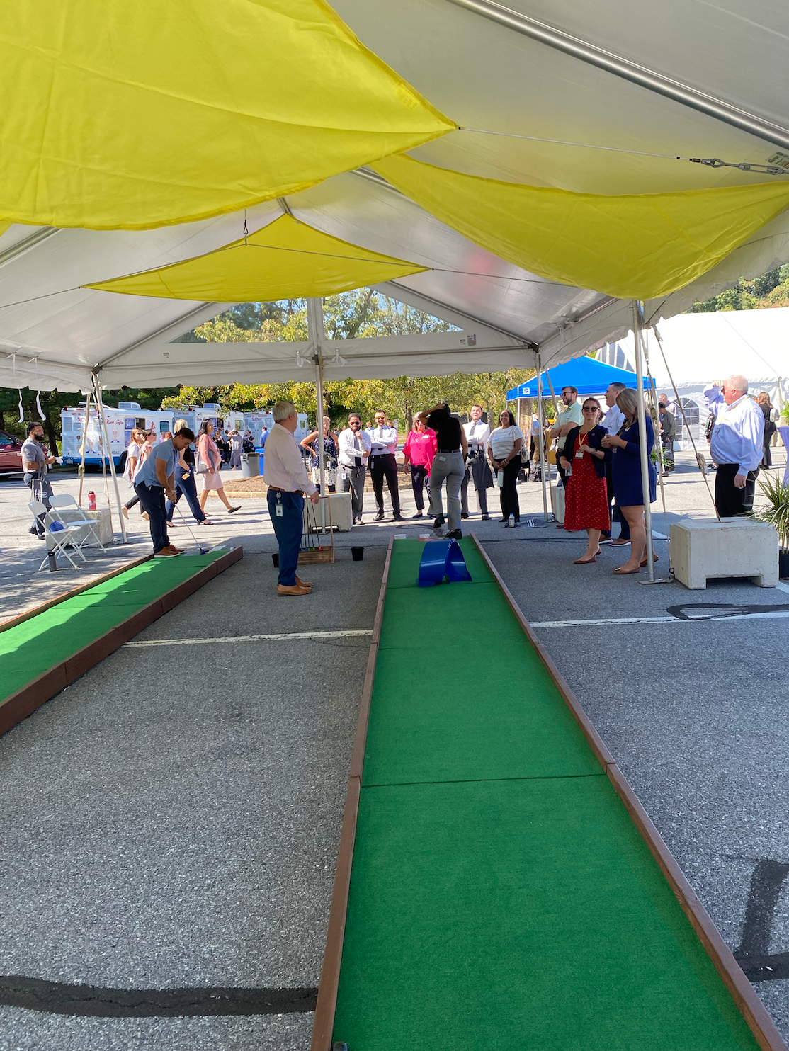 A group of people are playing bocce ball under a tent.