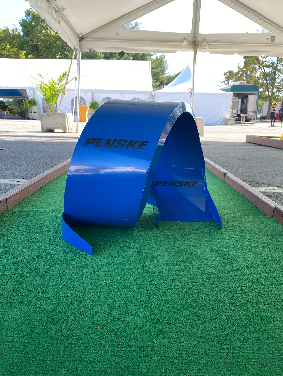 A blue sculpture is sitting on top of a green lawn under a tent.
