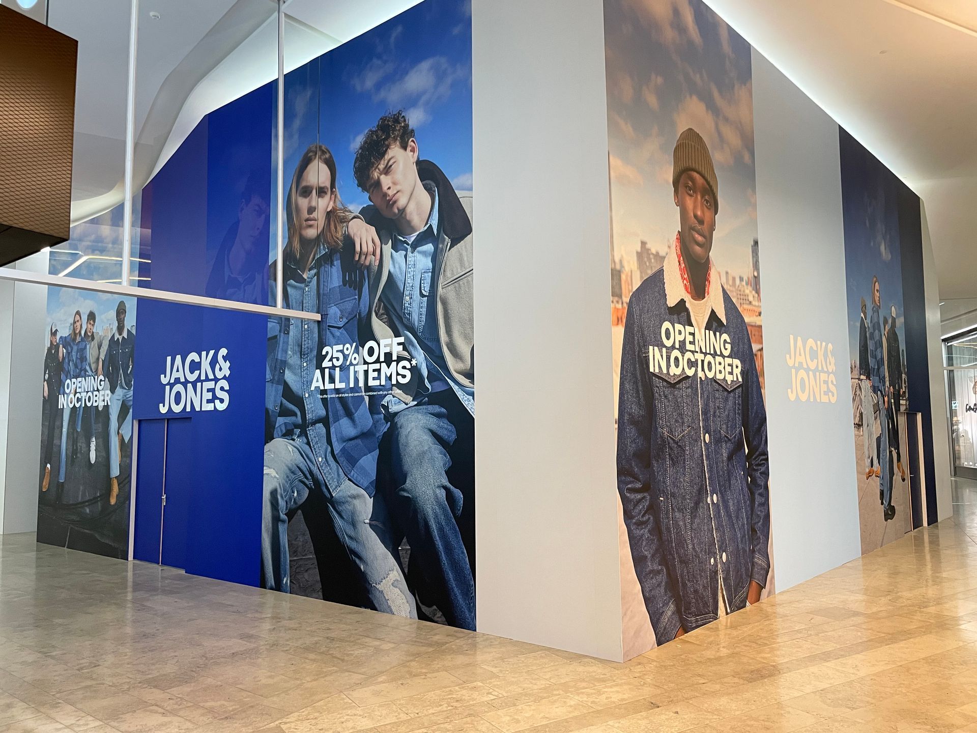 Een etalage van de kledingwinkel Jack & Jones met modellen op grote posters die reclame maken voor  in een winkelcentrum