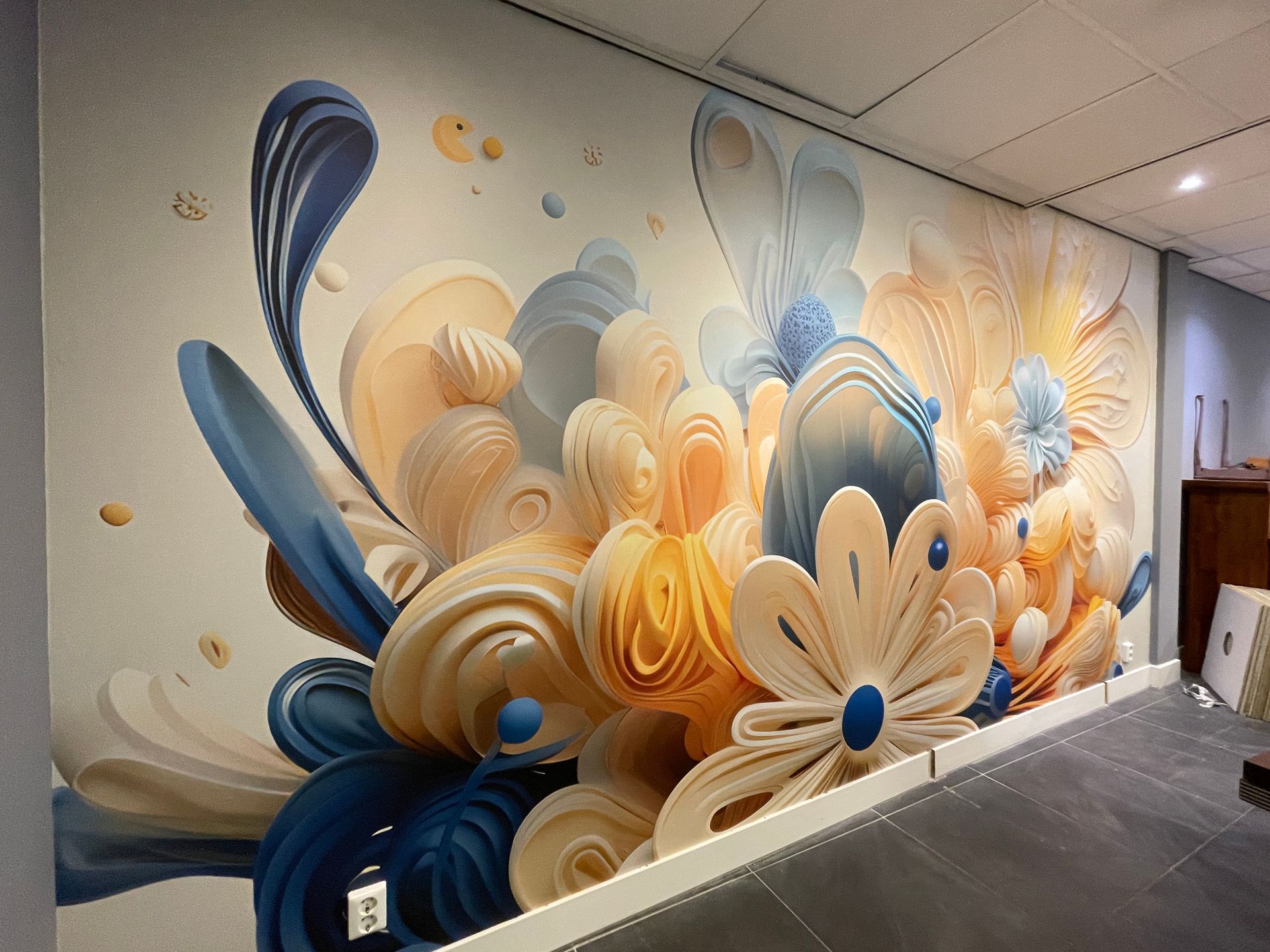 wallcovermet abstracte, 3D-achtige, gelaagde papieren vormen in zachte blauwe en crèmekleuren tegen een lichte achtergrond.