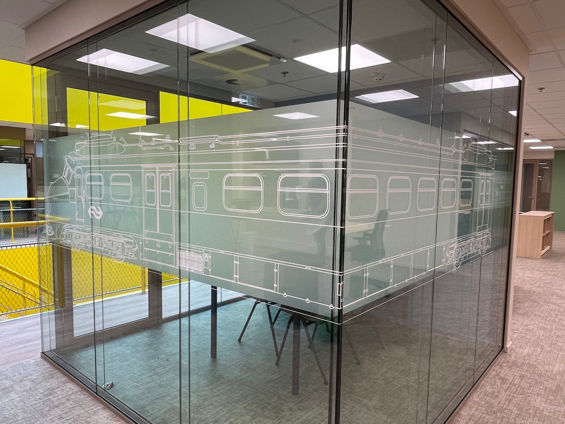 it's all about details Een moderne vergaderruimte met glazen wanden in een kantoor, met in het midden een wit geëtste omtrek van een treinstel.