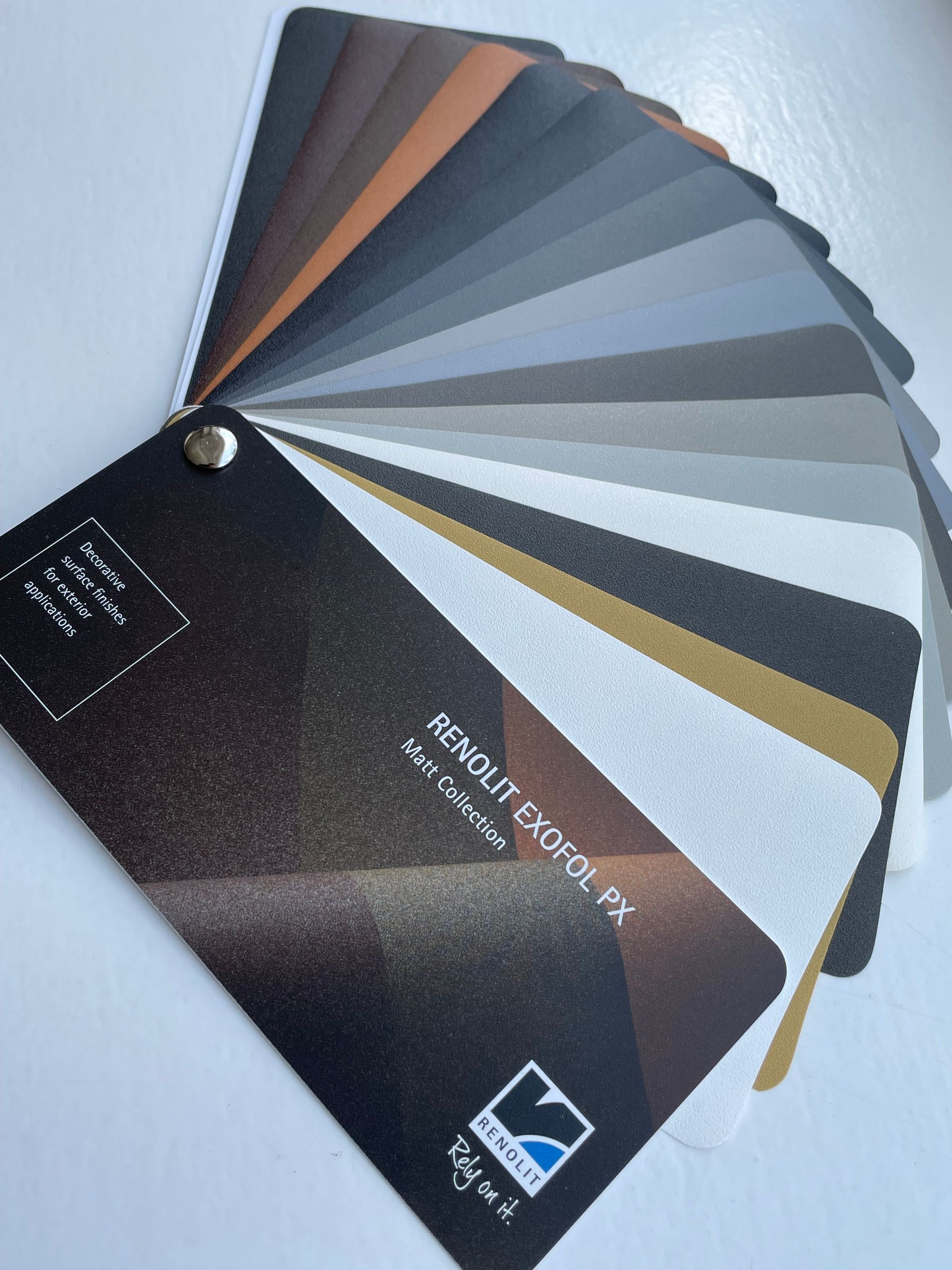 Een waaier met kleurstalen van gestructureerde verf, met een scala aan neutrale, metallic en aardetinten.