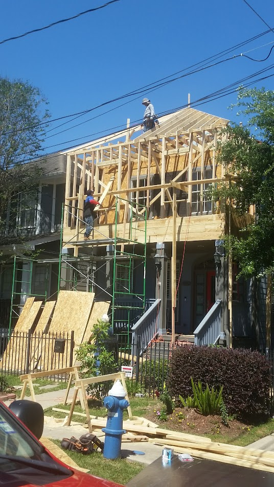 Under-stairs storage unit with drawers, shelves, and baskets; beige and white, against a wood and concrete staircase.