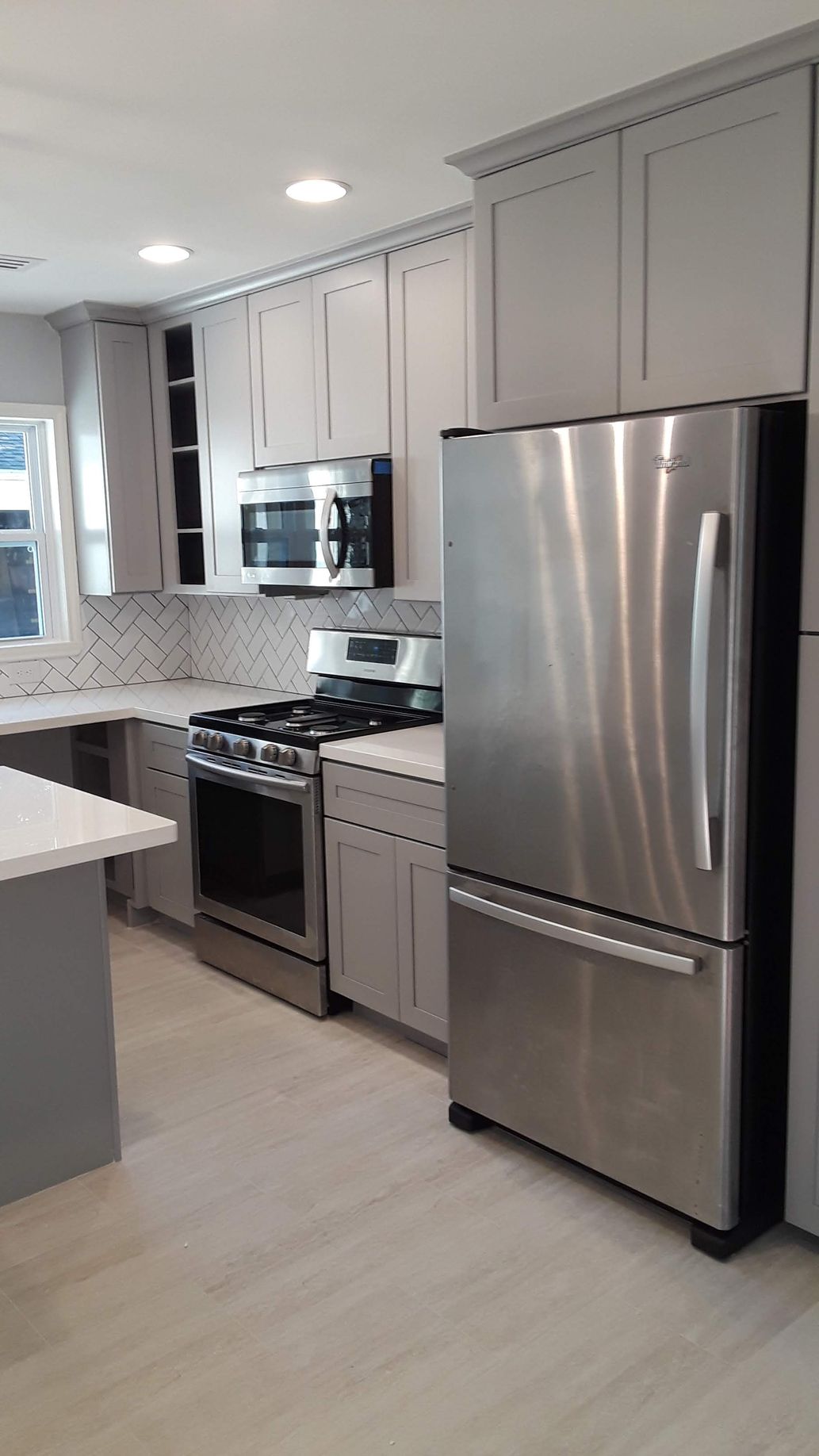 Gray kitchen with stainless steel appliances, light countertops, and cabinets.