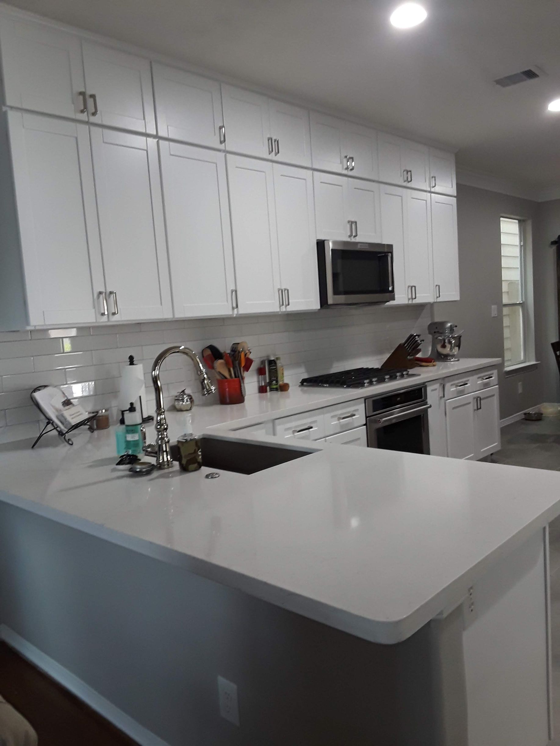 White kitchen with island, cabinets, appliances, and sink.