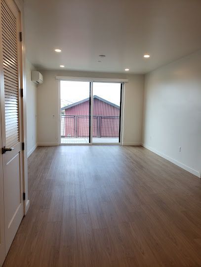 An empty living room with hardwood floors and sliding glass doors.