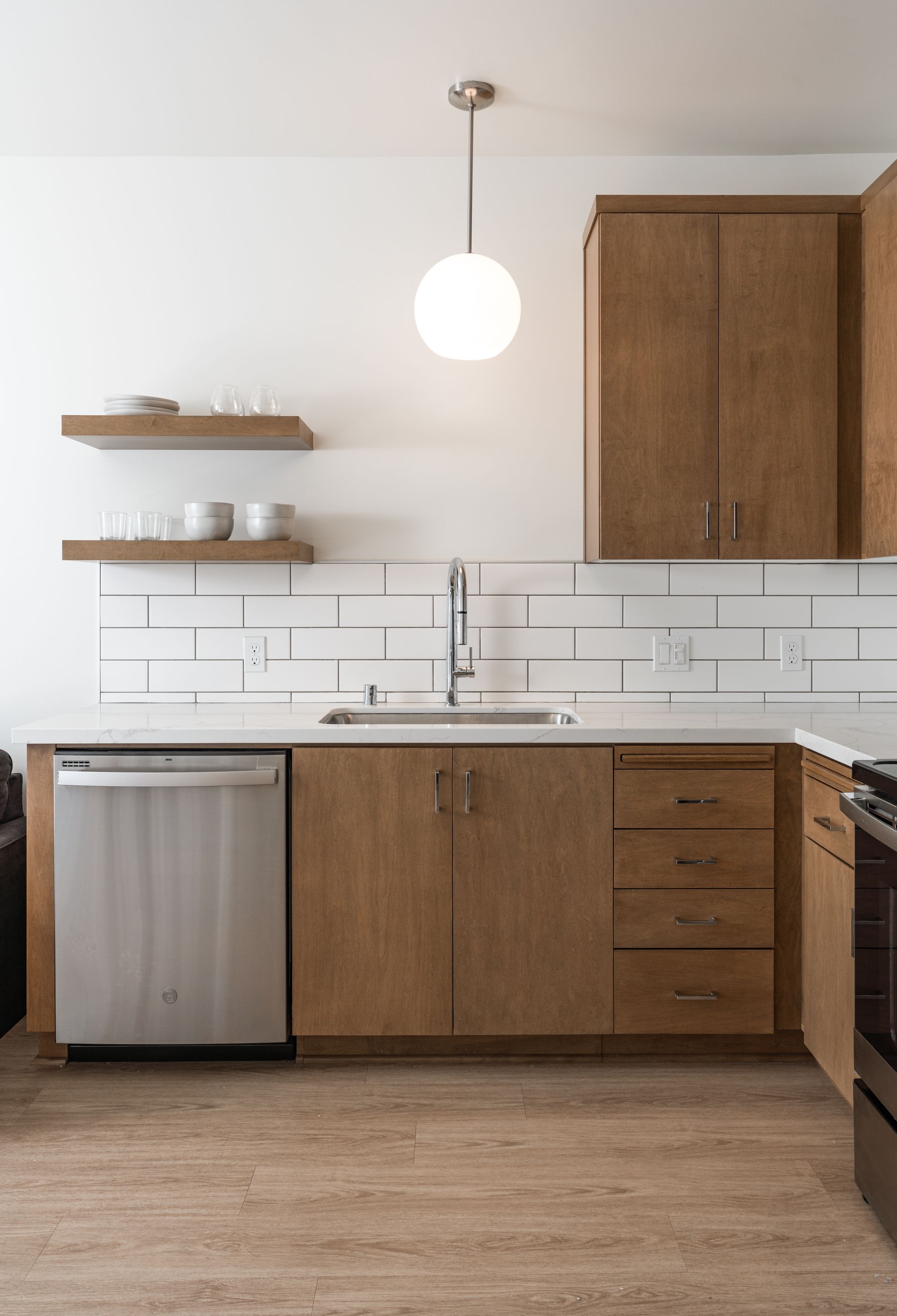 A kitchen with wooden cabinets , stainless steel appliances , a sink and a dishwasher.