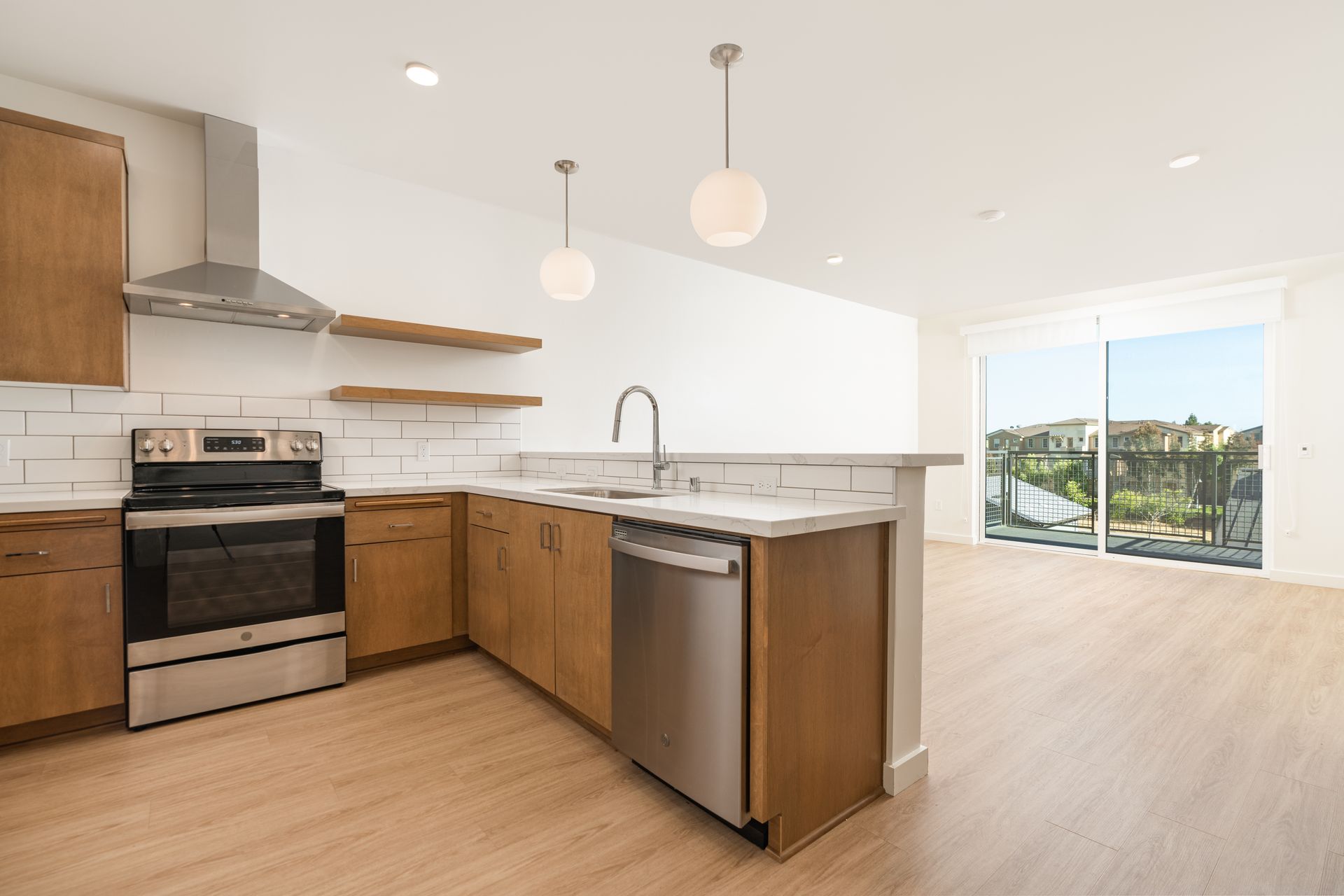 An empty kitchen with stainless steel appliances and wooden cabinets