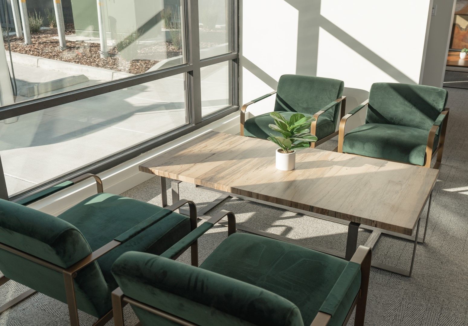 A living room with green chairs and a table with a plant on it.