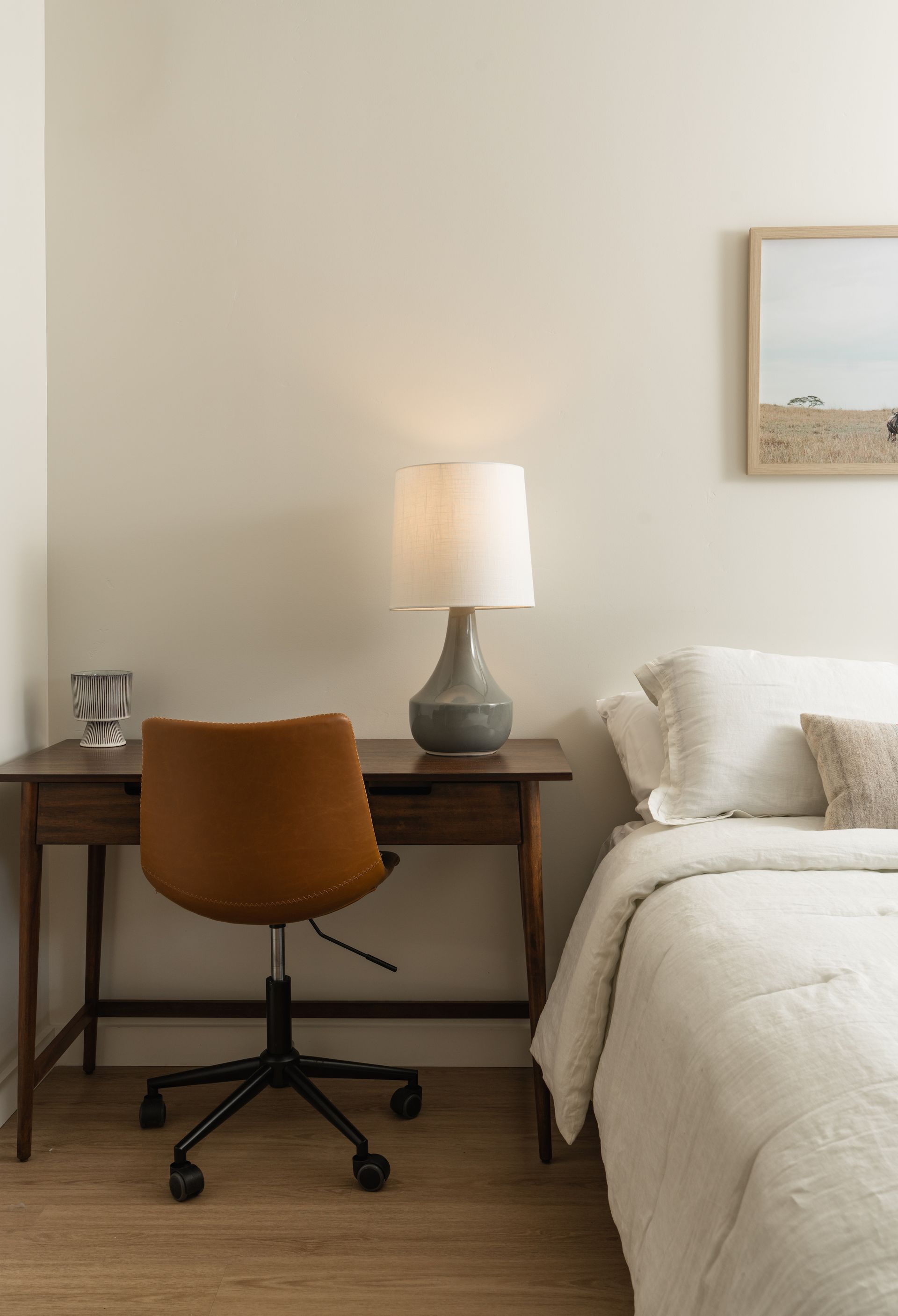 A bedroom with a bed , desk , chair and lamp.