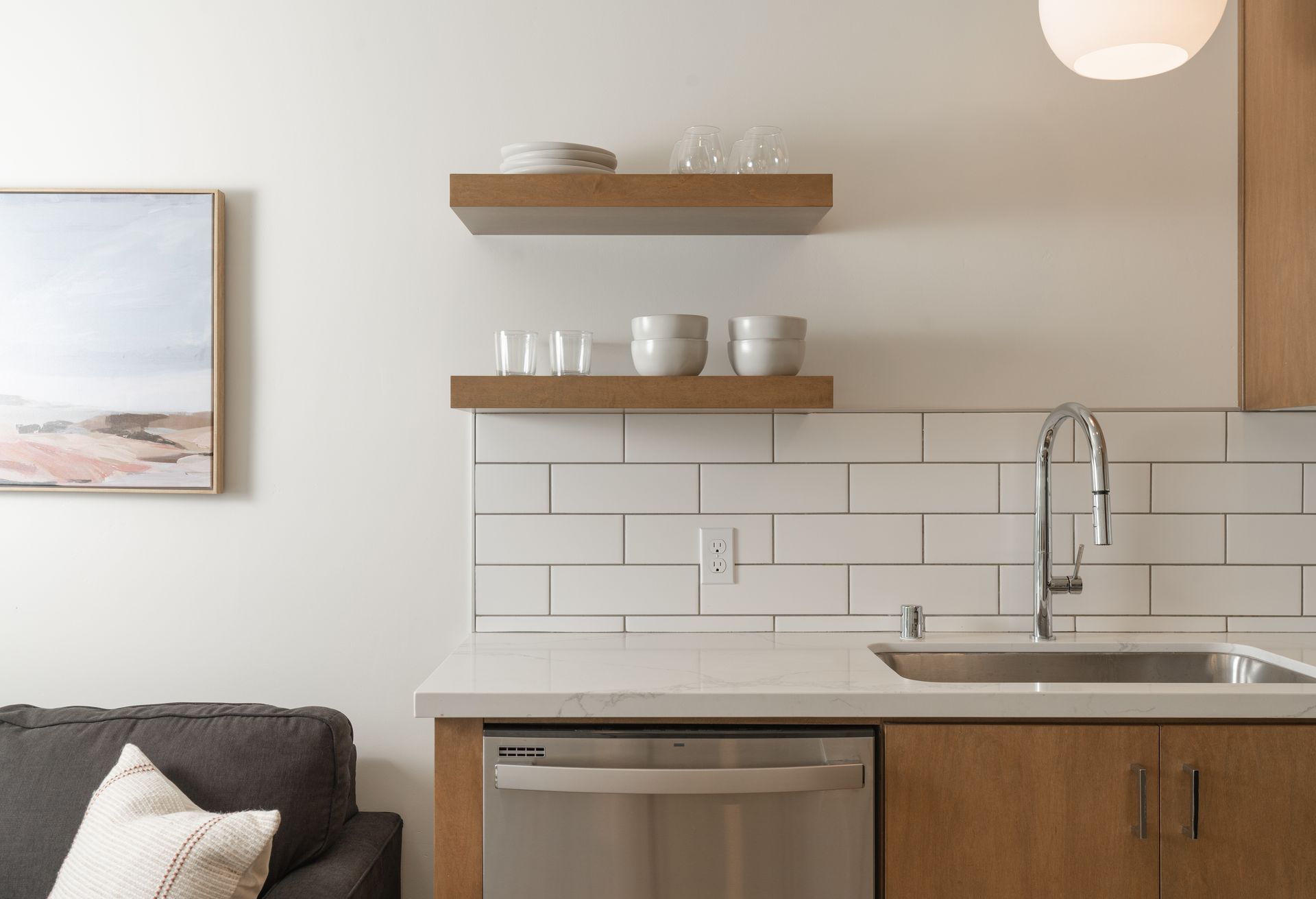 A kitchen with a sink , dishwasher , and a painting on the wall.