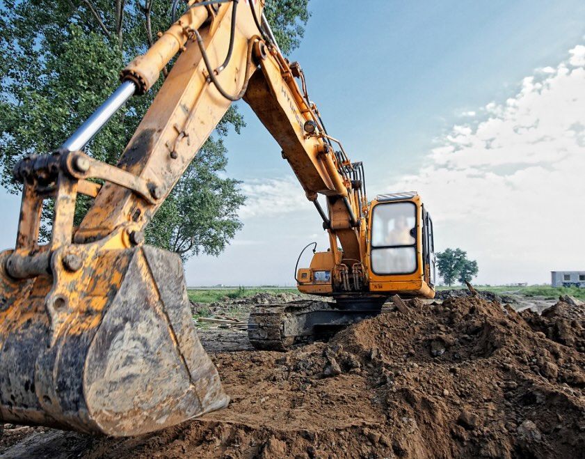 A yellow excavator is digging a pile of dirt on a construction site.