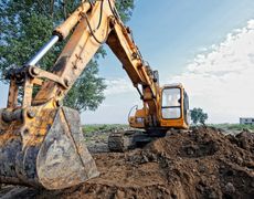 A yellow excavator is digging a pile of dirt on a construction site.