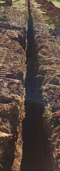 A trench is being dug in the dirt in a field.