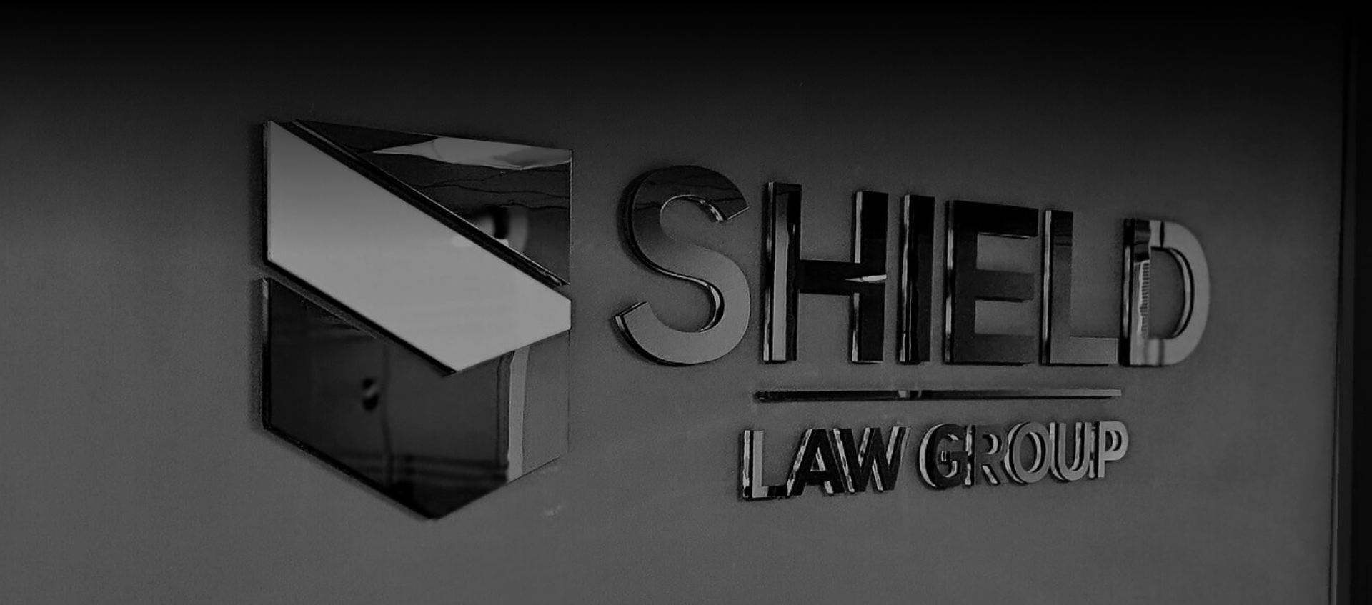 A black and white photo of a shield law group sign