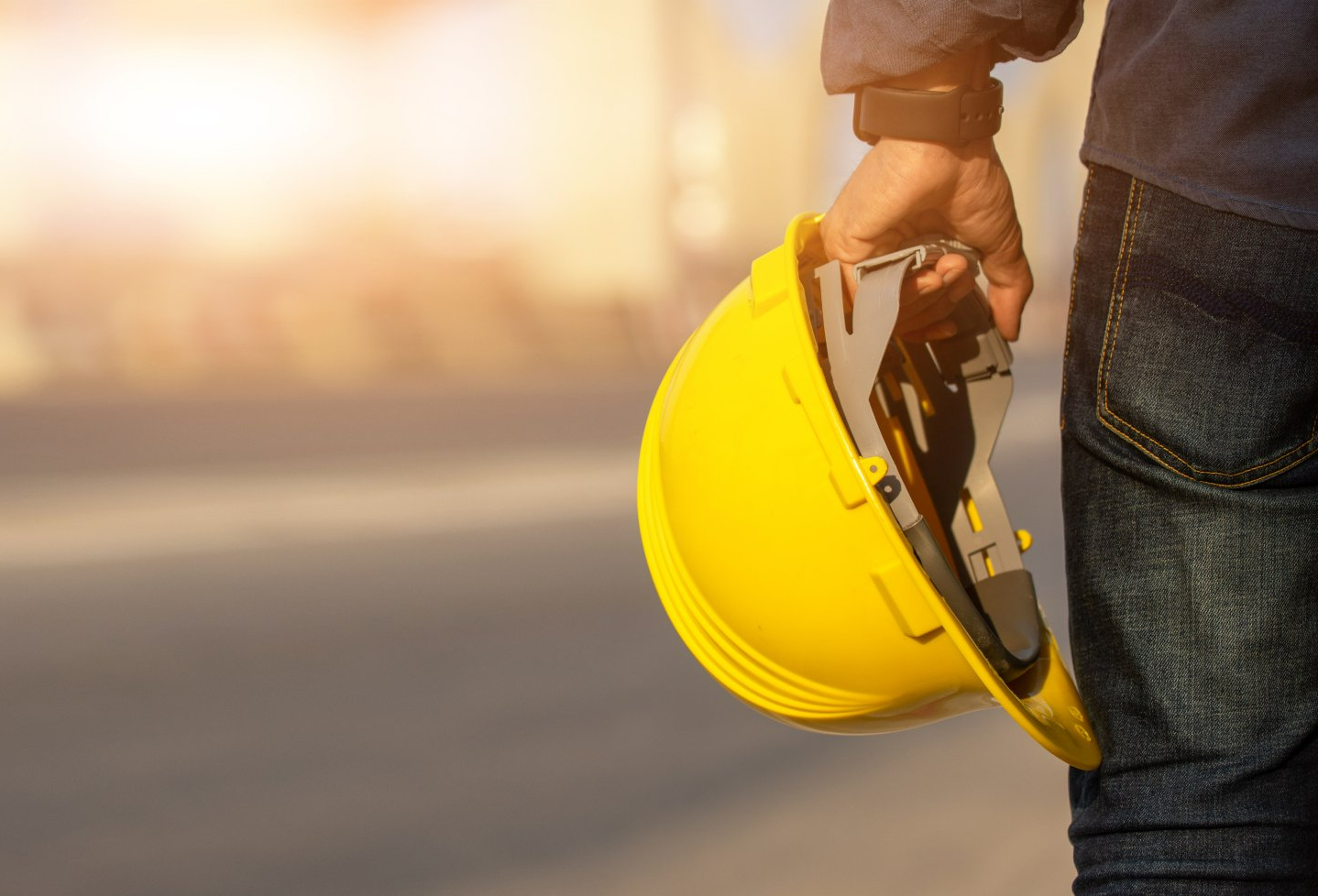 Close image of individual holding yellow hard hat with background blurred