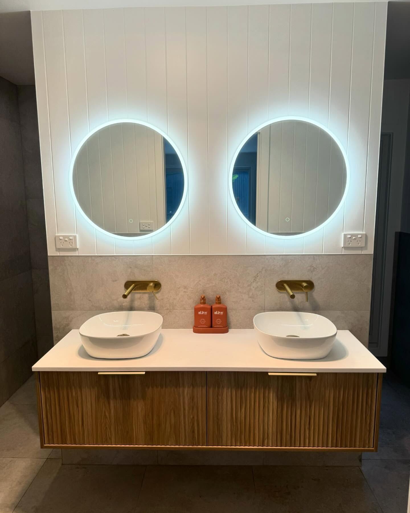 Double Bathroom Vanity With Round Lighted Mirrors and Gold Faucets — Chad Warrington Plumbing In Salamander Bay, NSW
