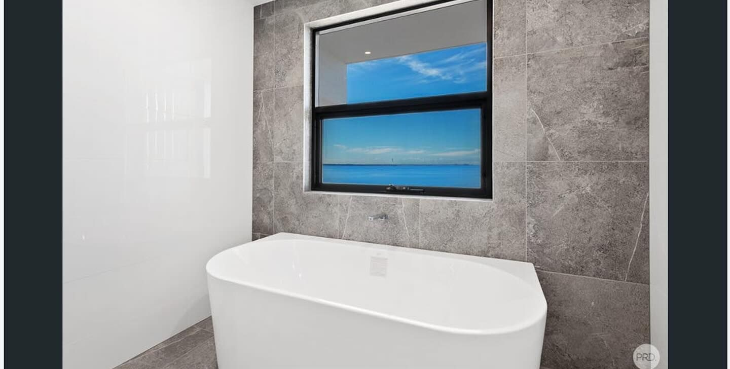 Modern Bathroom With a White Tub Under a Window — Chad Warrington Plumbing In Salamander Bay, NSW
