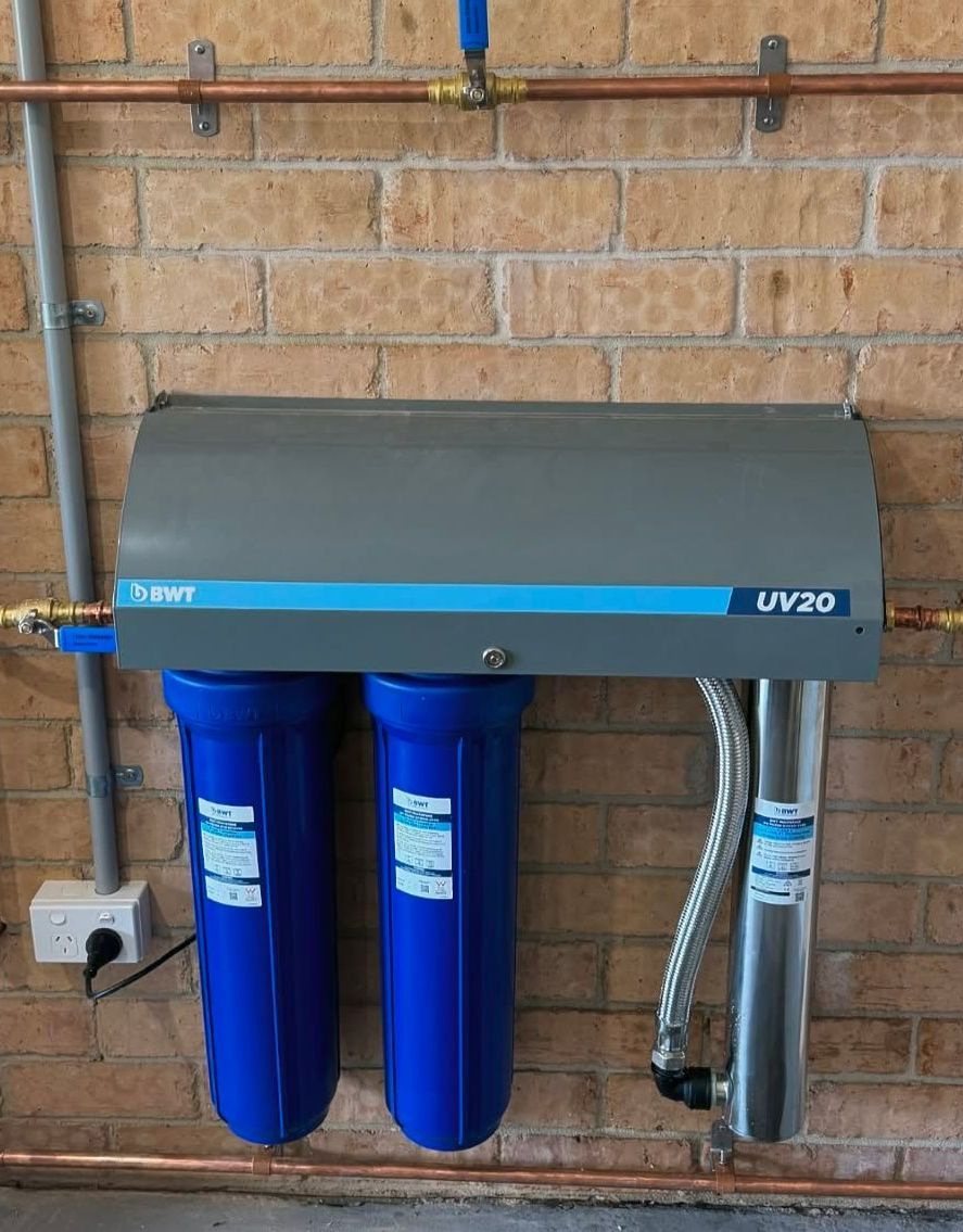 A Water Filter is Hanging on a Brick Wall — Chad Warrington Plumbing In Salamander Bay, NSW